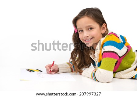 little girl lying on floor and smiling. side view of schoolgirl drawing picture
