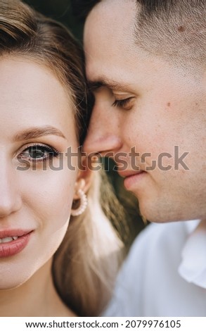 Wedding portrait, close-up photo of half of the faces of a beautiful, sweet blonde bride with curly hair and a stylish, smiling groom.