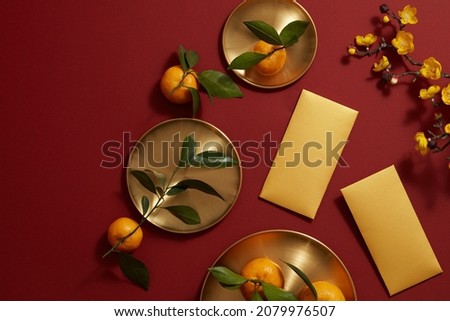 Chinese lunar new year with mandarin orange , flower and red pocket in red background , photography Tet holiday content , top view