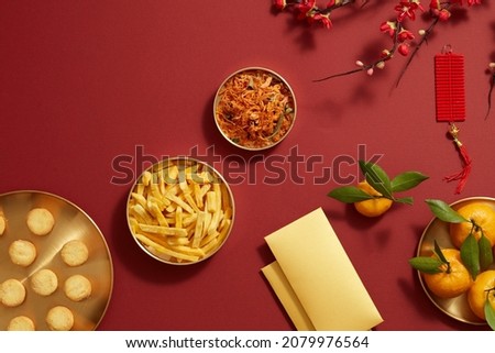 Chinese new year holiday with mandarin orange candy jam , fried potato teapot , flower and red pocket biscuit in golden dish , photography Tet holiday content , top view