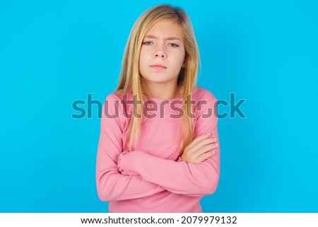 caucasian little kid girl wearing long sleeve shirt over blue background Pointing down with fingers showing advertisement, surprised face and open mouth