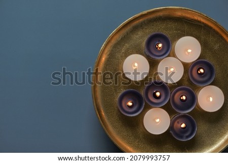 Candle flame. Burning candles in a round gold tray on a blue background