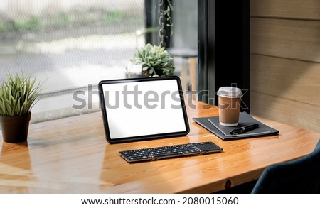 Mockup blank white screen portable tablet on wooden table in living room.