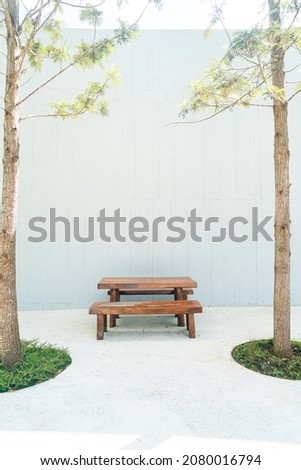 empty wood outdoor patio table and chair set with white wall