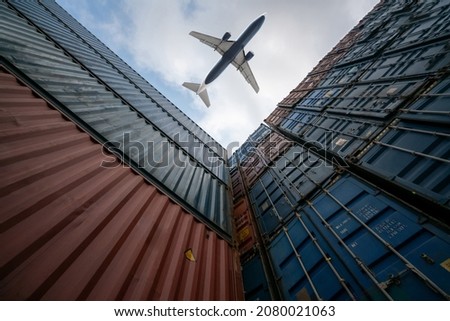 Freight airplane flying above overseas shipping container . Logistics supply chain management and international goods export concept . Royalty-Free Stock Photo #2080021063