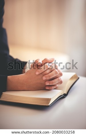focus on woman's hand While praying for Christianity with blurry body background, praying with her hands with scriptures.