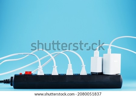 Surge protector with connected white wires of electrical appliances on a blue background. Free space Royalty-Free Stock Photo #2080051837