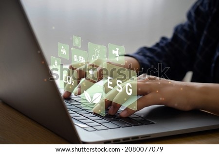 Young man sitting using a computer to analyze ESG, environment, conservation, society, governance, close to the computer screen in business investment strategy concept.