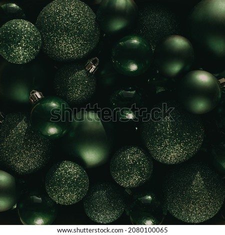 Flat lay with heap of green christmas balls with various size and texture, glittering and shining, lying on surface, imitating christmas tree. New year decoration, holiday arrangements
