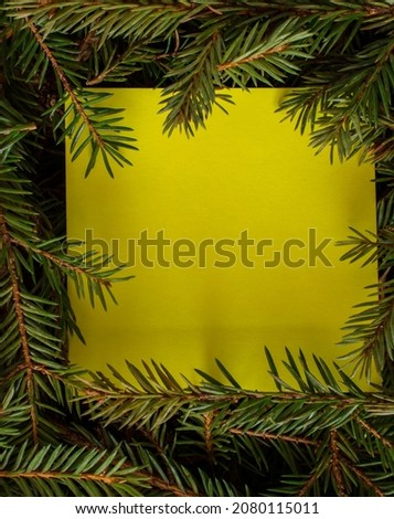 a yellow sticker is placed inside the branches of the Christmas tree. space for text. flat lay.