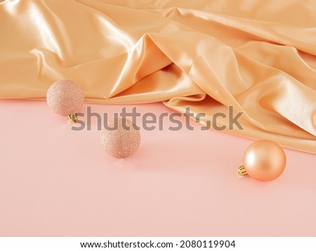 Creative vintage Christmas composition with modern golden bauble on pastel pink table against shiny golden curtain. Retro futurism scene with copy space