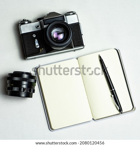 Old family photos on wooden background. Vintage pictures, camera, notepad and modern notebook. Flat lay. Blank notebook with fountain pen and retro camera on wooden table. 