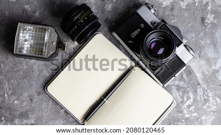 Old family photos on wooden background. Vintage pictures, camera, notepad and modern notebook. Flat lay. Blank notebook with fountain pen and retro camera on wooden table. 