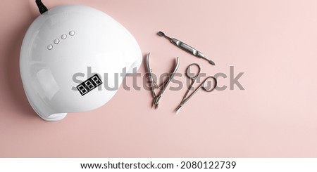  A set of manicure tools: scissors for a haircut and a cuticle pusher and a UV lamp for drying shellac on nails  Royalty-Free Stock Photo #2080122739