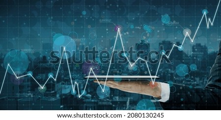 Close up of businessman hand holding tablet with abstract glowing business chart on blurry grid night city bokeh background. Digital economy and big data concept. Double exposure