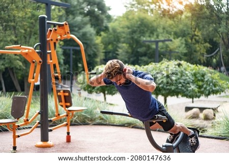 Hyperextension exercise. Charismatic man trains at the open air gym. Outdoor fitness background. Royalty-Free Stock Photo #2080147636