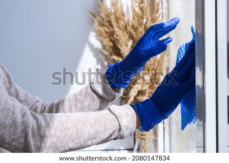 Employee hand in rubber protective glove with micro fiber cloth wiping window from dust. General spring cleaning. Housework and housekeeping concept. Wiper with a dirty window from the outside Royalty-Free Stock Photo #2080147834