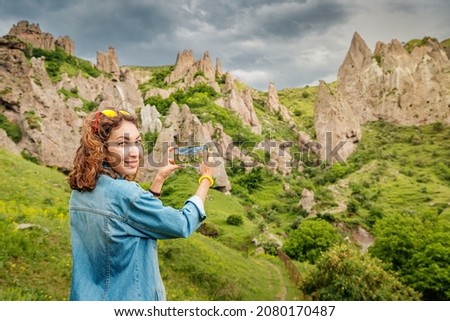 Asian woman travel blogger taking photos of amazing ancient cave dwellings in a city carved out of soft sandstone rocks