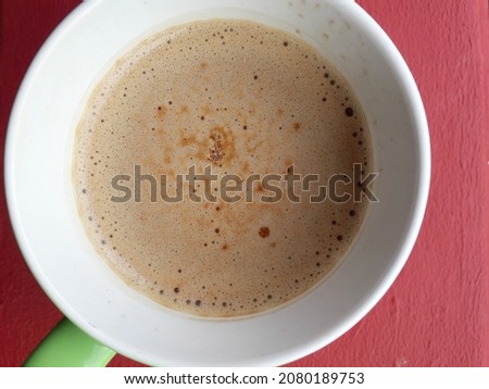 A cup of coffee is placed on the table on a red background