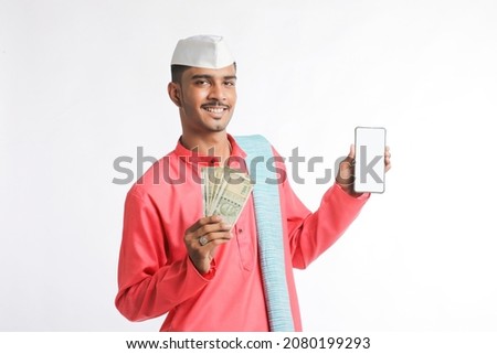 Young indian farmer showing smartphone and money on white background.