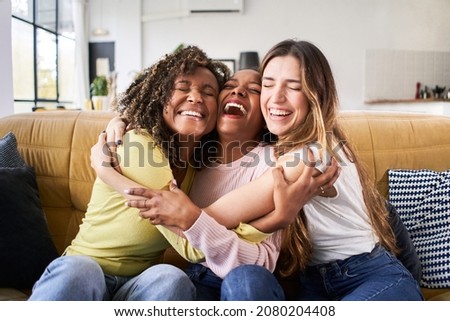 Three happy friends hugging smiling.Funny women together celebrating sitting on the living room sofa Royalty-Free Stock Photo #2080204408