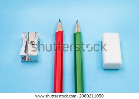 Two pencils, sharpener and eraser on blue background. Top view. School concept, selective focus