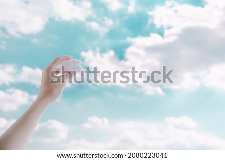 Hands holding clouds in the sky.