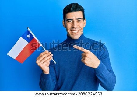 Handsome hispanic business man holding chile flag smiling happy pointing with hand and finger 