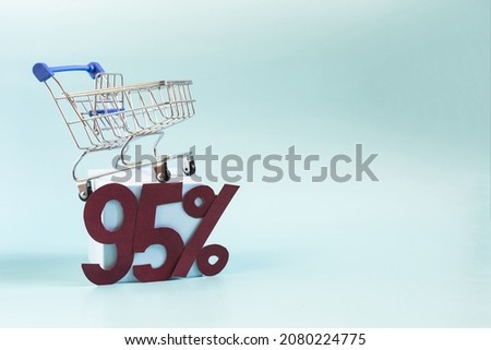An empty metal basket from the store on a light podium and the figure 95% on a blue background close-up. The concept of discounts and sales in trade