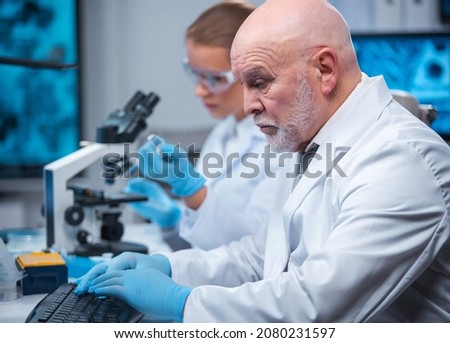 Professor and doctor work in a modern scientific laboratory using equipment and computertechnologies. Group of scientists make research and develop new vaccines. Science and healthcare concept.