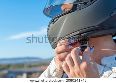 young female biker fastening her safety helmet to ride a motorcycle. safety and protection concept on the road