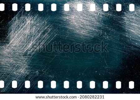 Dusty and grungy 35mm film texture or surface. Perforated scratched camera film isolated on white background. Royalty-Free Stock Photo #2080282231