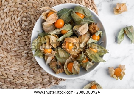 Ripe physalis fruits with dry husk on white marble table, flat lay Royalty-Free Stock Photo #2080300924