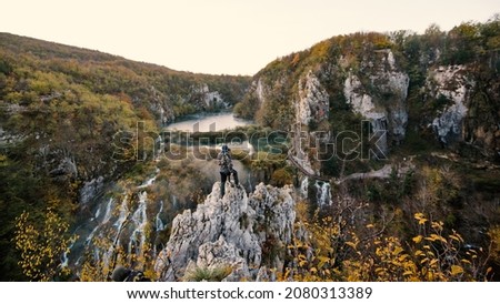 Aerial scenic view of turquoise water and waterfall with man standing in the foreground in the Plitvice Lakes National Park. Croatia. Europe.