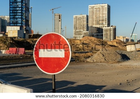Photo of the construction site, building of high buildings and cranes. Red and white circle stop road sign. Constructional concept.