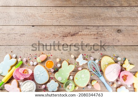 Easter cooking baking background with pastel colored easter cookies, sugar sprinkles and ingredients for bake cake and cookies.  Wooden rustic background, flatlay banner copy space