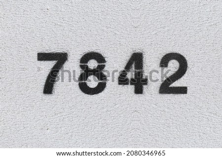 Black Number 7842 on the white wall. Spray paint. Number seven thousand eight hundred forty two.