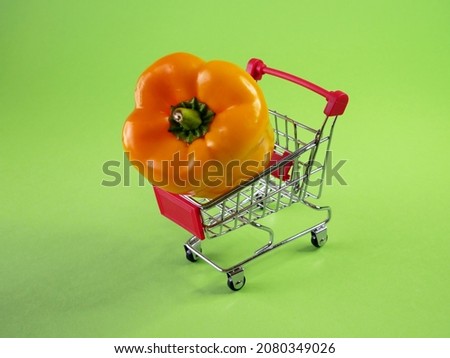 shopping trolley moving with yellow sweet pepper on green chroma key background,  green grocery delivery concept, closeup