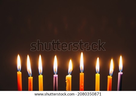 Jewish Holiday Hanukkah background with candles and traditional candelabra menorah on dark background. Jew festival of lights concept