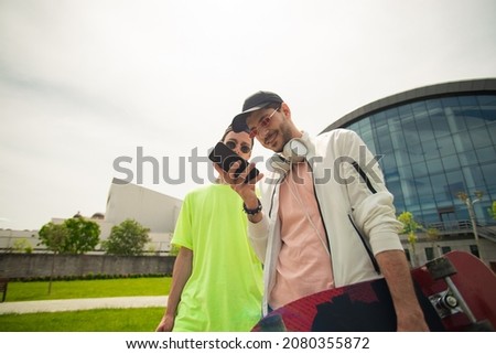 Two handsome male friends are smiling while checking the phone