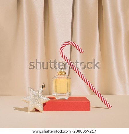 Minimal stylish holiday present composition with golden perfume , Christmas ornament and candy cane. Trendy vintage concept.