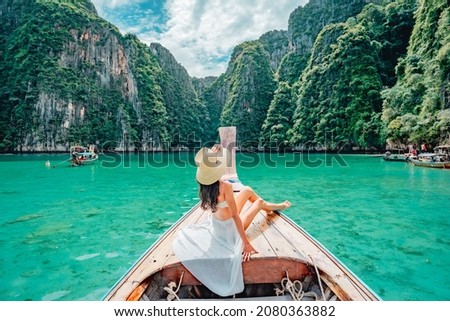 Young woman in swimsuit enjoying on traditional long-tail Boat over beautiful mountain and ocean, Phi phi Islands, Thailand Royalty-Free Stock Photo #2080363882