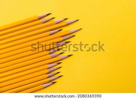 A row of yellow pencils on yellow background.