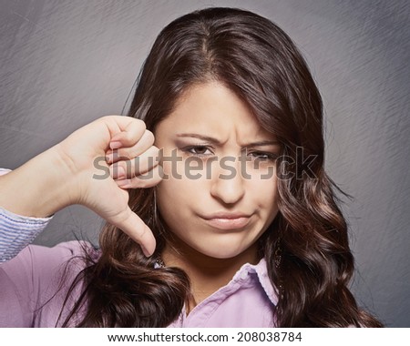 Thumb down sign, young woman with unhappy negative expression 