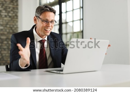 Joyful businessman celebrating his  success while using a computer  in the office