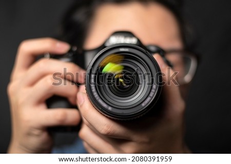 photographer take pictures Snapshot with camera. man hand holding with camera looking through lens.Concept for photographing articles Professionally. Royalty-Free Stock Photo #2080391959