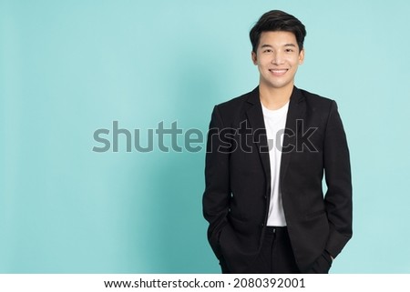 Smiling young Asian businessman in black suit isolated on green background Royalty-Free Stock Photo #2080392001