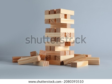 Jenga tower made of wooden blocks on grey background Royalty-Free Stock Photo #2080393510