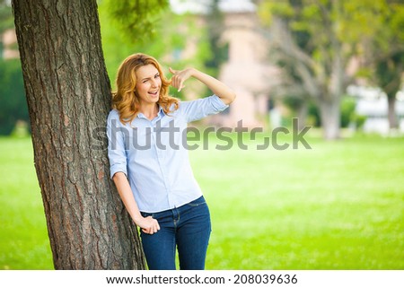 Beautiful Young Woman Relaxing Outdoors. Meadow. Beauty Girl Enjoying Nature. Making phonecall sign