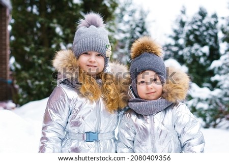 Two little cheerful children on snowy frosty day. Brother and sister play outdoors in winter in a ski suit. Sincere children's emotions in the snow. Awesome winter outdoor activities for kids